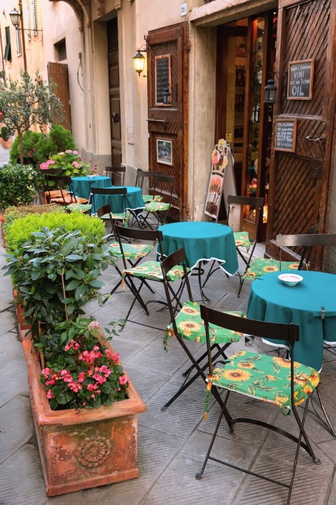 Typical small cafe in Tuscany, Italy, with blue table clothes and green sunflower cushions on the seats, with a cute chalkboard