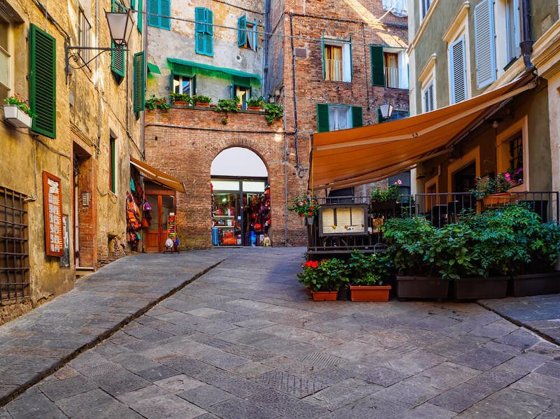 Street scene in Siena with brick buildings and more modern buildings too
