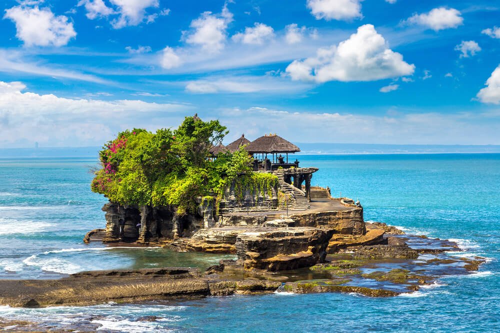 Ocean view of Tanah Lot temple in Canggu area of Bali, which has the temple set literally on an island in the ocean, with waves receding around low tide
