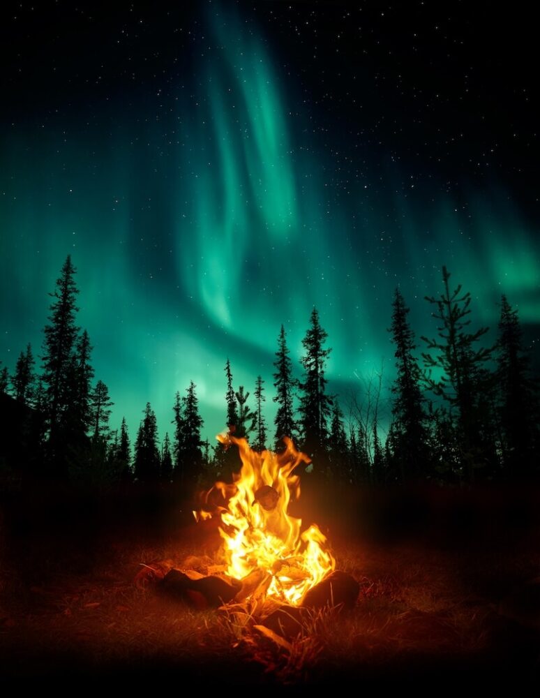 View of the northern lights overhead with bonfire in the foreground