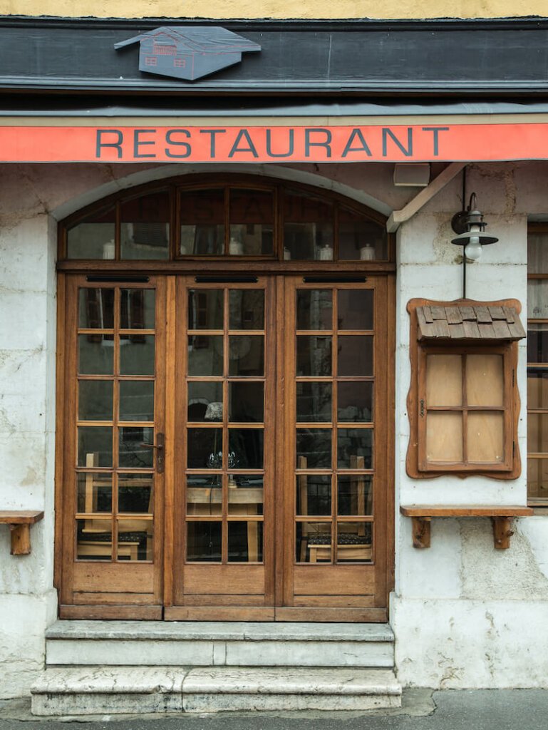Sign for a restaurant in Annecy with the red awning and lettering that reads restaurant