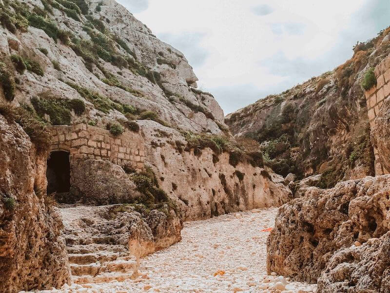 A rugged landscape in Malta in January when the crowds are minimal with caves and stairs on a sandy beach