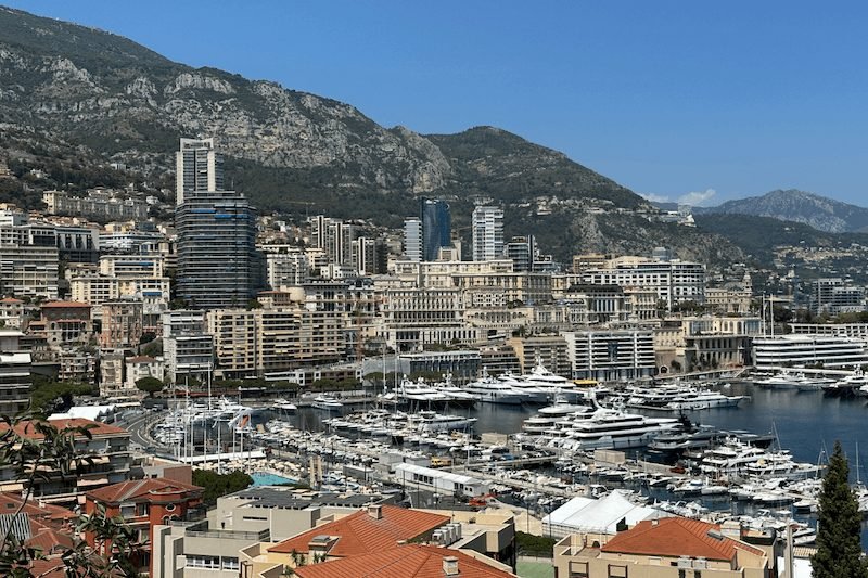 View of apartments, yachts, mountains, and harbor in the city-state of Monaco along the French Riviera