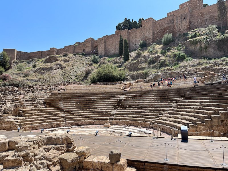 The gorgeous architectural detail of the archaeological ruins of the roman theater with a half-amphitheater and the architecture around it crumbling with a few tourists visiting in the off season