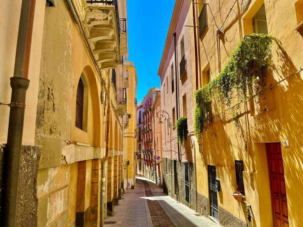 the lively streets of the town of cagliari italy with pastel colored earth tone buildings on a sunny day where the city is not crowded