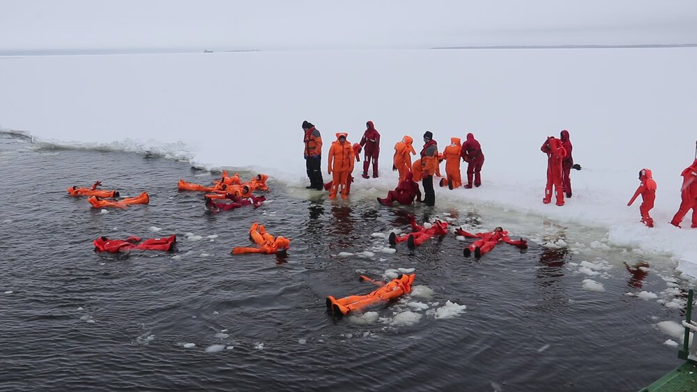 Ice floating in orange survival suits in daytime in Finland