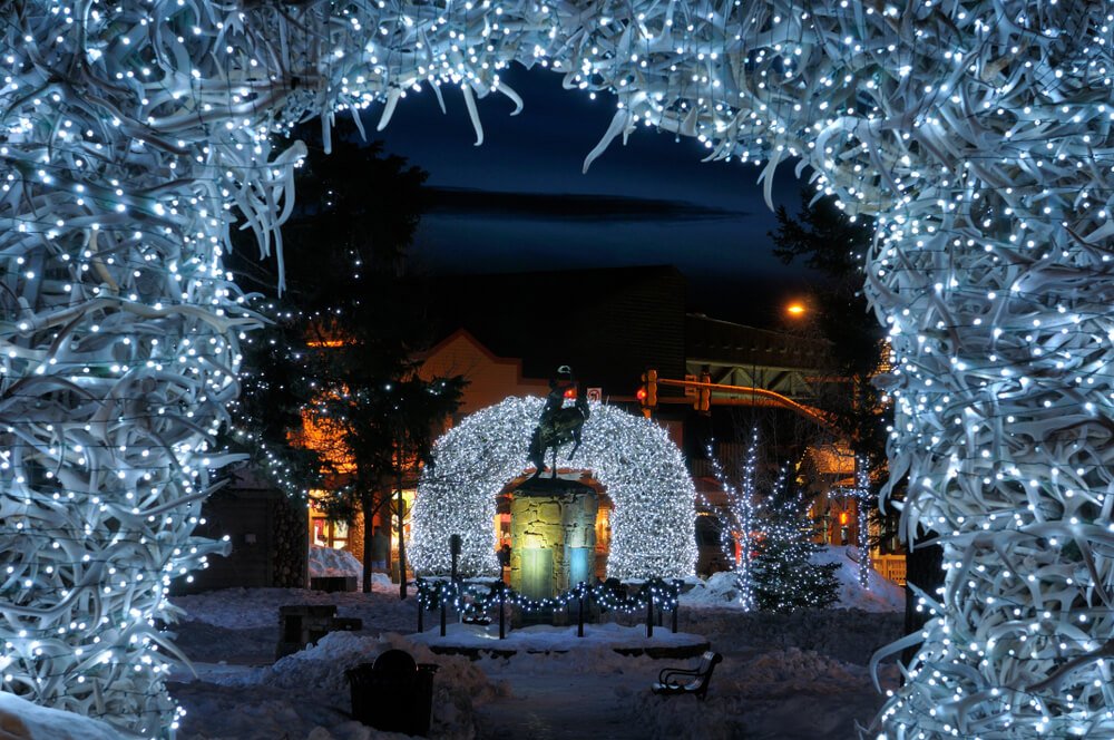 Lit up antlers with Christmas lights in Jackson Wyoming with white lights and festive color and snowfall on the ground