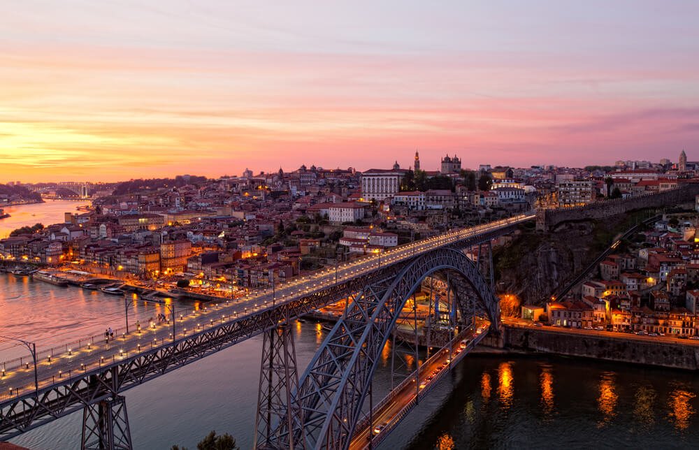 Bridge of Luis I at night over Douro river and Porto cityscape with the lights twinkling on behind it, on a beautiful winter night.