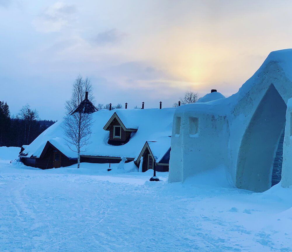 The exterior of the unique Rovaniemi snow hotel with the sun low on the horizon in the winter during limited daylight hours on a Lapland afternoon