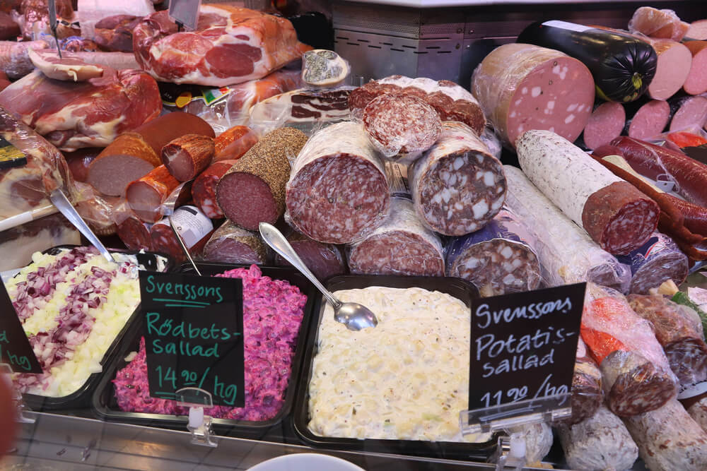 A selection of cured meats and salads with Swedish signs for what they are and how much they cost per kilo