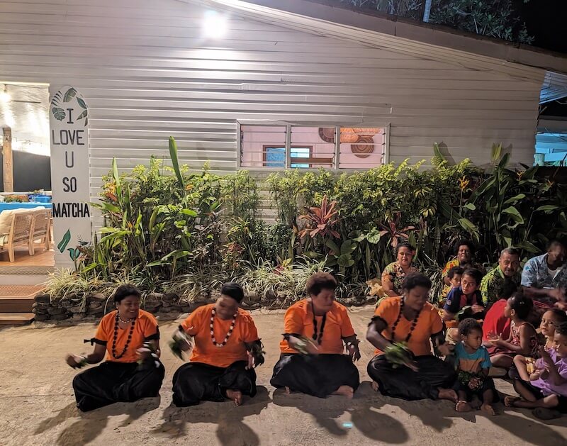 Fijian locals sitting in front of the restaurant while in orange shirts about to perform a dance