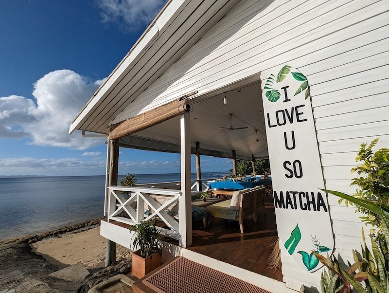 Sign on a surfboard that reads I love you so matcha on a beachfront restaurant