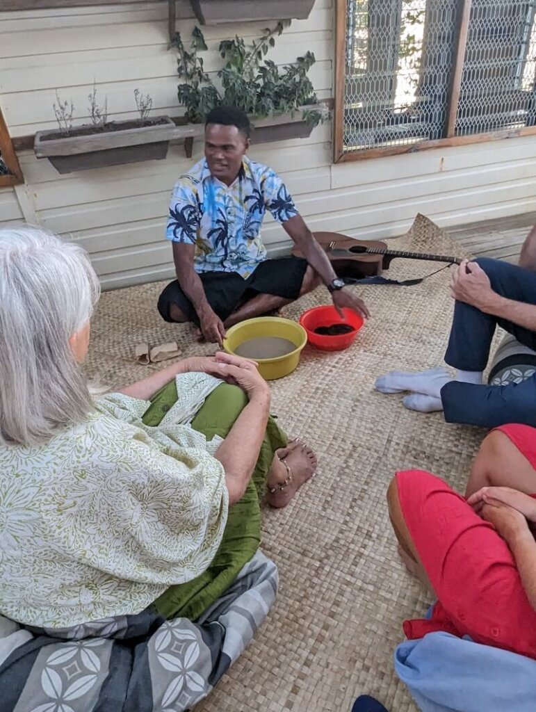 Group sitting around with a Fiji local drinking kava at a ceremony