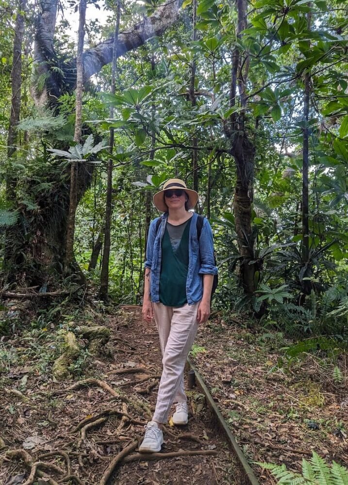 Allison hiking in tavoro waterfalls area wearing linen pants, open shirt, and shoes