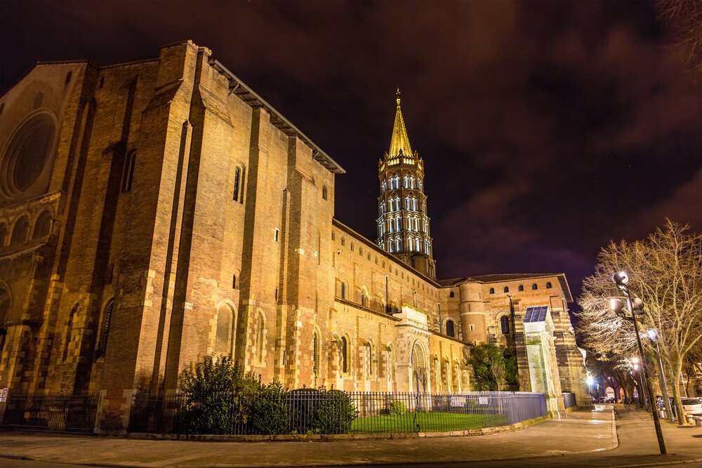 Toulouse at night with the St Sermin church lit up beautifully in the winter with bare trees showing the time of year