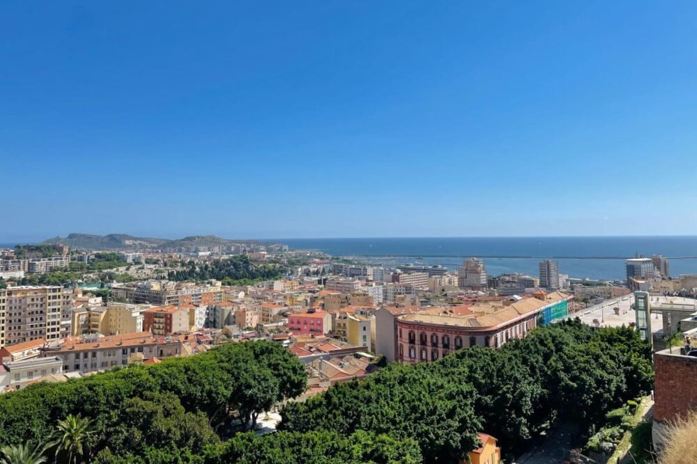 View of the city of Cagliari from above with the sea in the distance and trees and houses