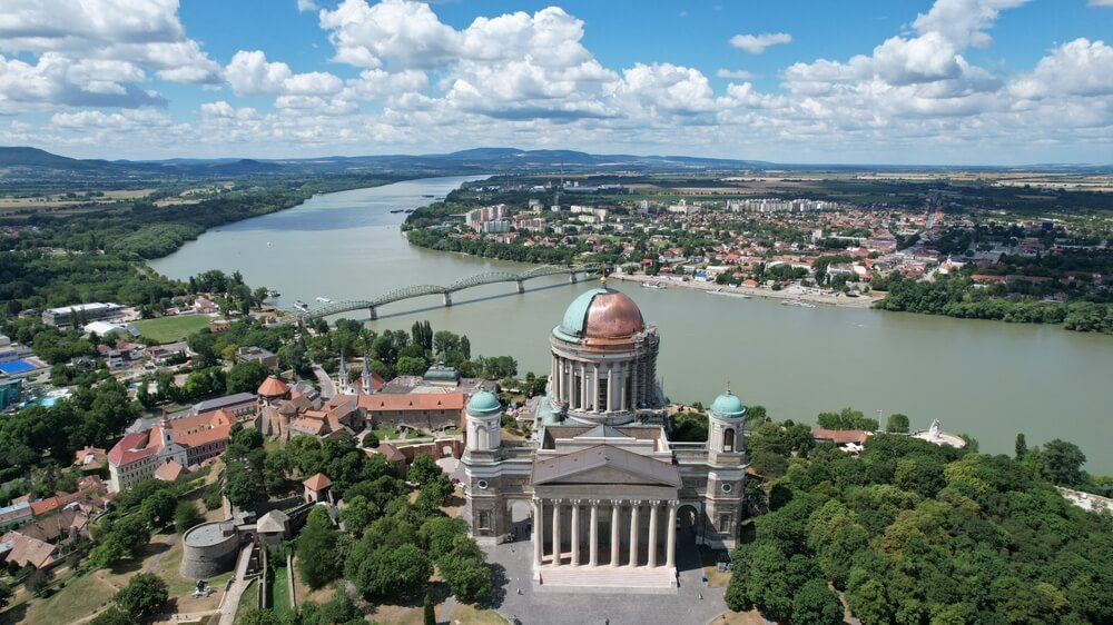 Aerial view of the Cathedral of Our Lady and Saint Adalbert in Esztergom,  with a view of the bend in the danube river, slovakia in the distance.
