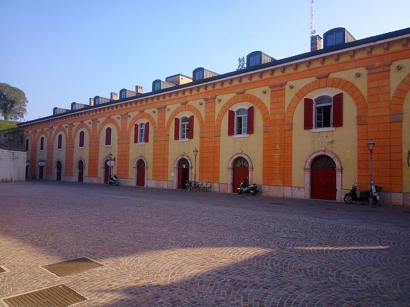 Orange and yellow museum with red shutters and vespas in front