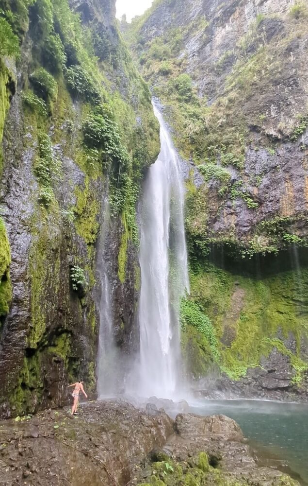 Allison in front of the Savulelele Waterfall, a tiny figure you see only in contrast to the size of the waterfall