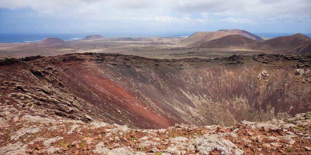 view over volcanic crater of Calderon Hondo with red and brown streaked volcanic landscape