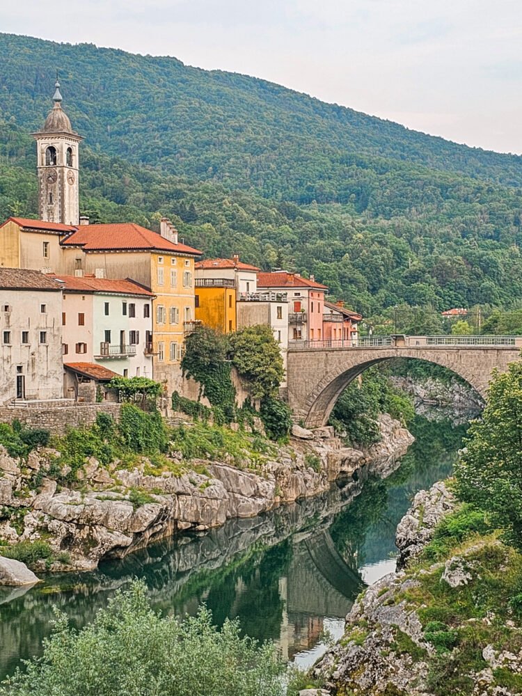 the unique riverside town of kanal ob soci in Slovenia along the river with an arched stone bridge and old fashioned stone architecture and fairytale aesthetic