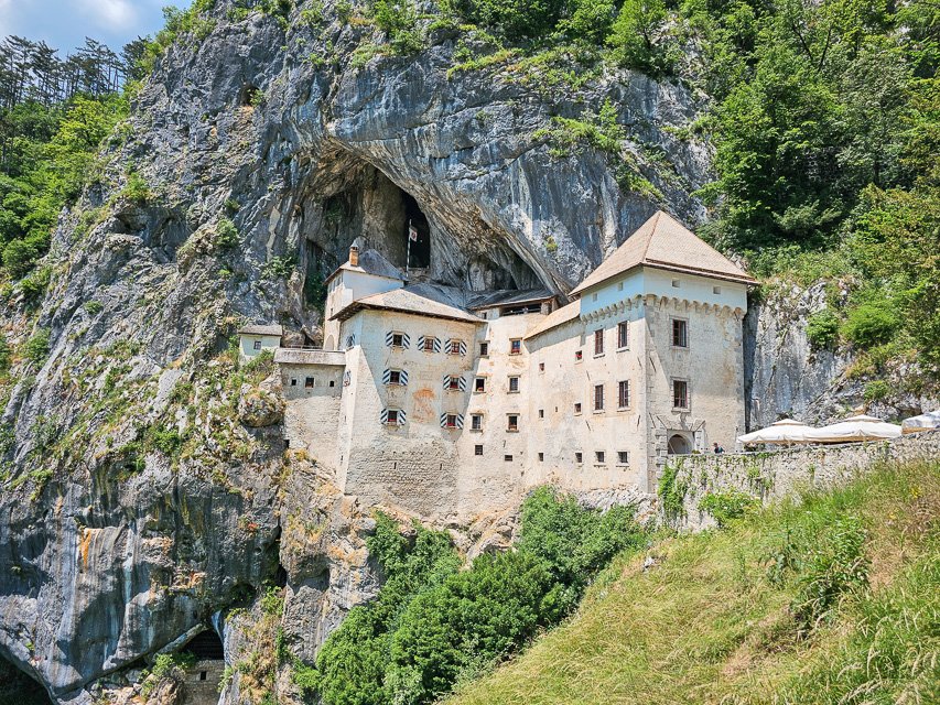 view of a castle built into the side of the wall in Slovenia which is also part of a cave complex