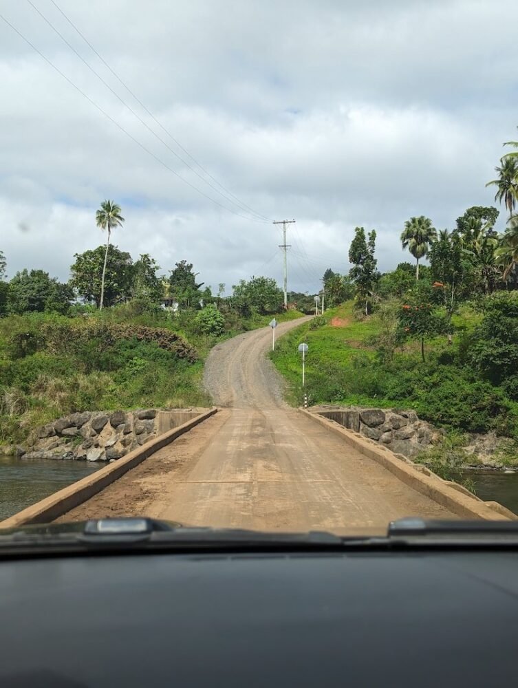 The road to savuelele with a bridge going over a waterway and then very dusty, gravel road up ahead of the end of the bridge