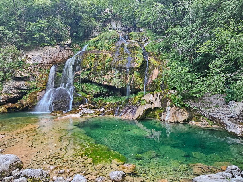 the virje waterfall, a series of small waterfalls cascading over a large rock and forming a beautiful natural swimming pool at the foot of the waterfall