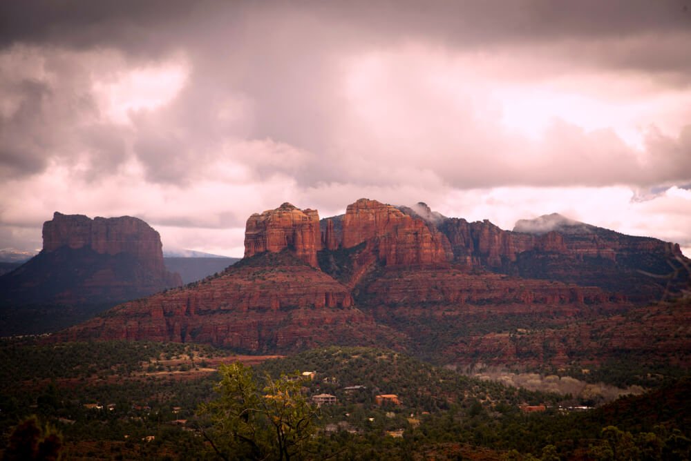 Sedona winter landscape at sunset with pink clouds illuminating the beautiful red rocks of the mountain ranges