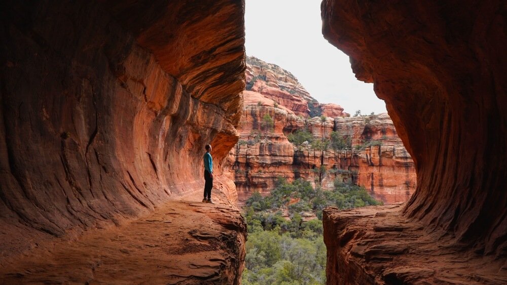 Person in long shirt and long pants hiking in Subway Cave in sedona in the fall or winter months when it's a little cold out but no snow out