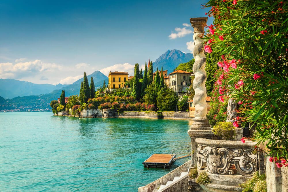 Villa Monastero gardens in Italy with pink flowers and pillar and view fo the town in the distance as well as the lake