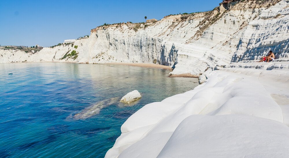 people sitting on the white cliff edges of the scala dei turchi in sicily
