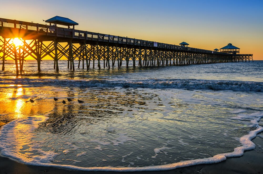 folly beach pier in charleston with sunset behind it