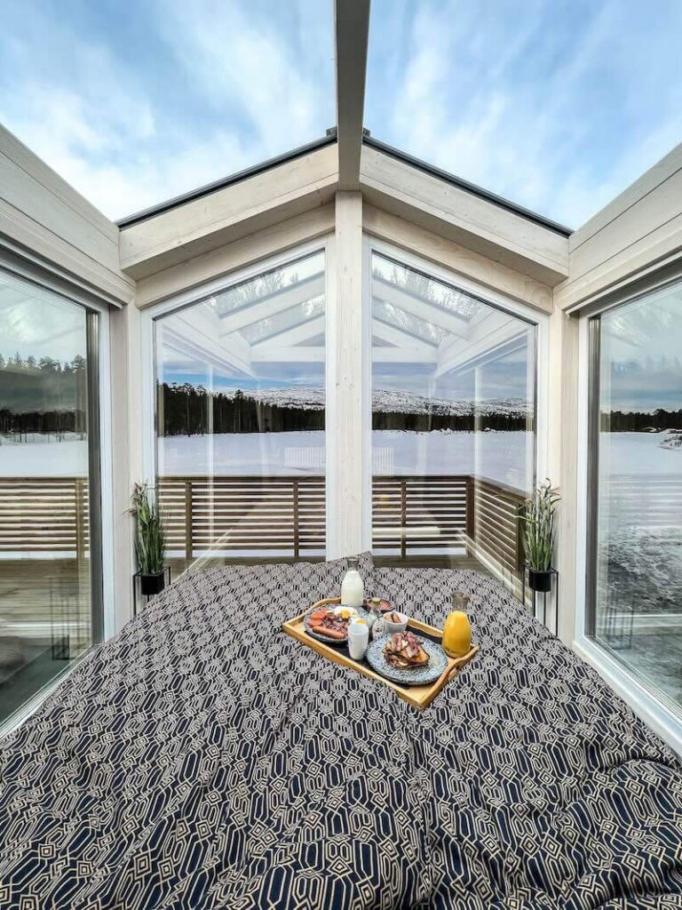 Breakfast served on top of a bed with glass roof and walls