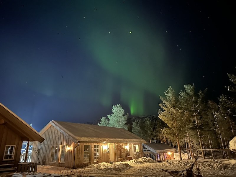 The aurora in Alta over a snow-covered cabin