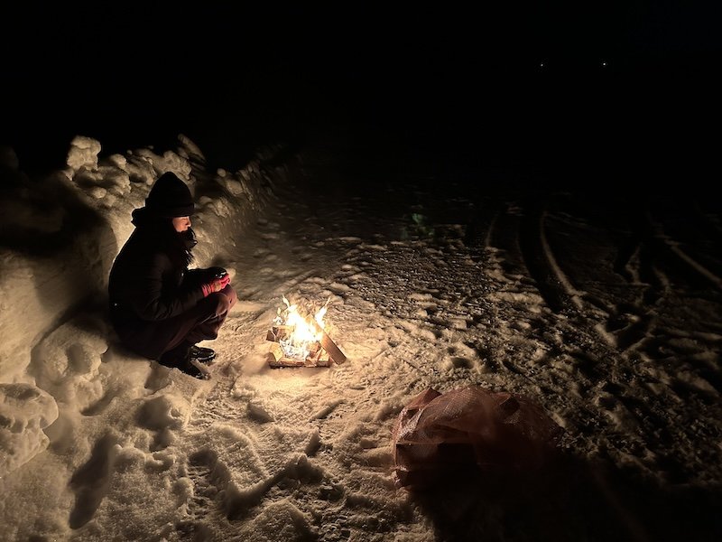 Person sitting in a parking lot with a bonfire