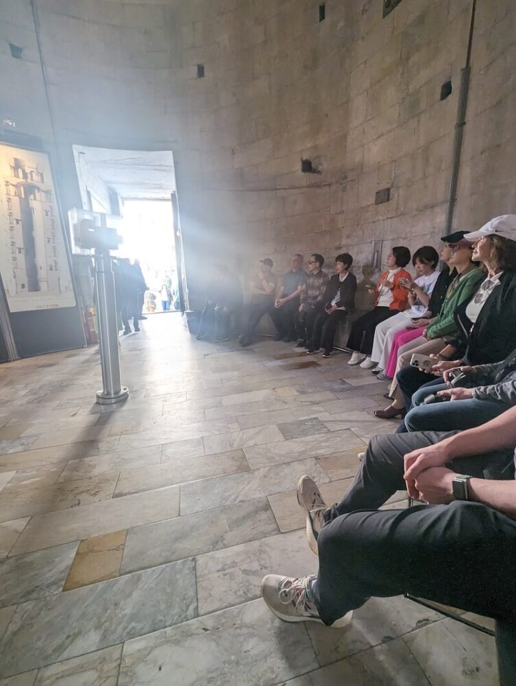 People waiting and listening to a presentation while sitting inside the hollow part of the leaning tower of pisa