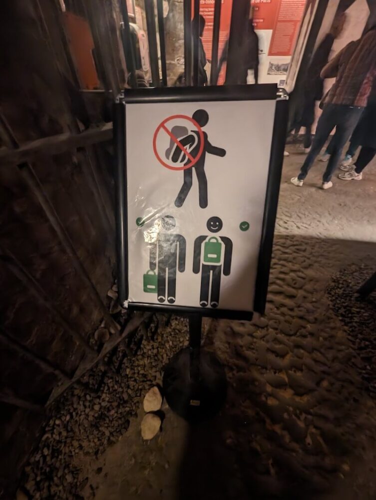 Backpack sign showing that you are allowed to bring backpacks but you must wear them on your front