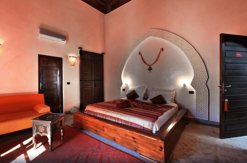 Pastel salmon pink guestroom with moroccan style furnishing on bed