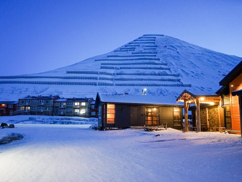 Avalanche fencing on the mountain and small houses with cozy warm glows in lights coming off the houses