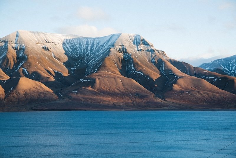 A bit of remaining snow on top of a mountain in front of the town of Longyearbyen, on a summer's clear sunny day with blue sea