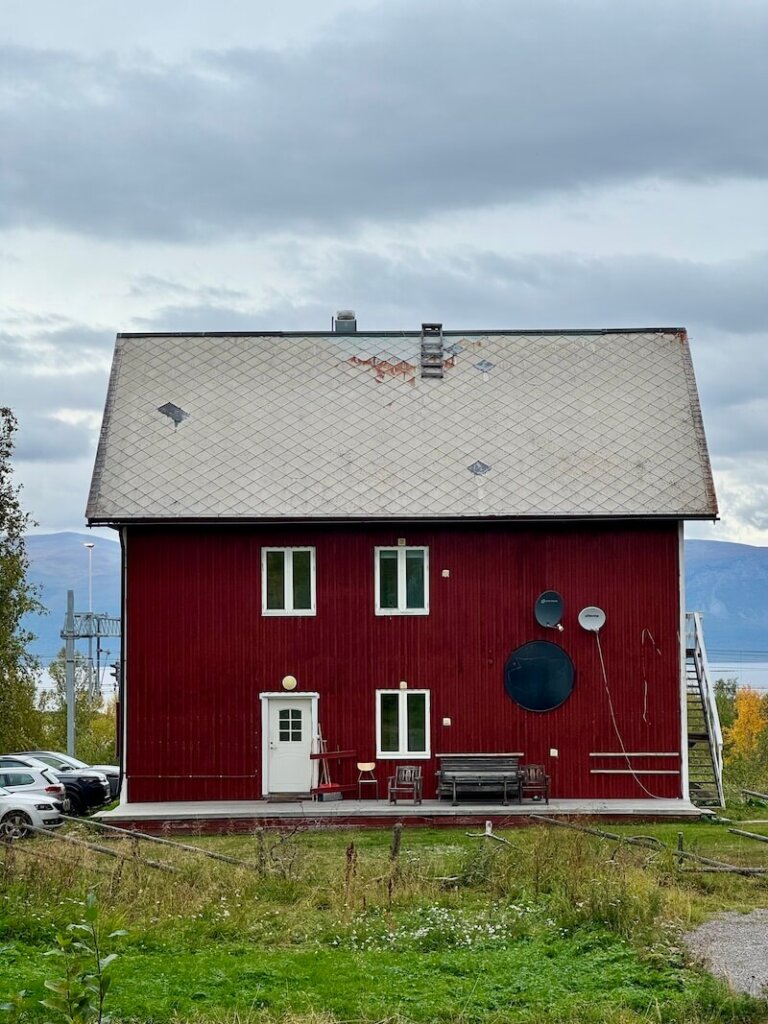 Red painted building in Abisko in front of the lake and mountains