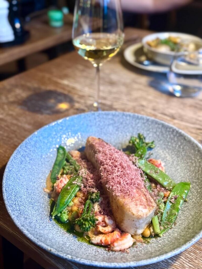 Meal at Abisko Mountain Lodge using seasonal ingredients: white fish with crayfish, pasta, and peas