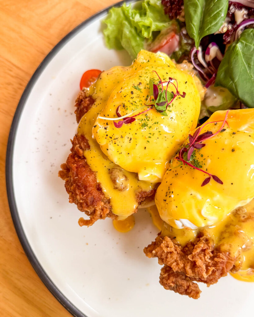 brunch of eggs benedict with fried chicken and salad