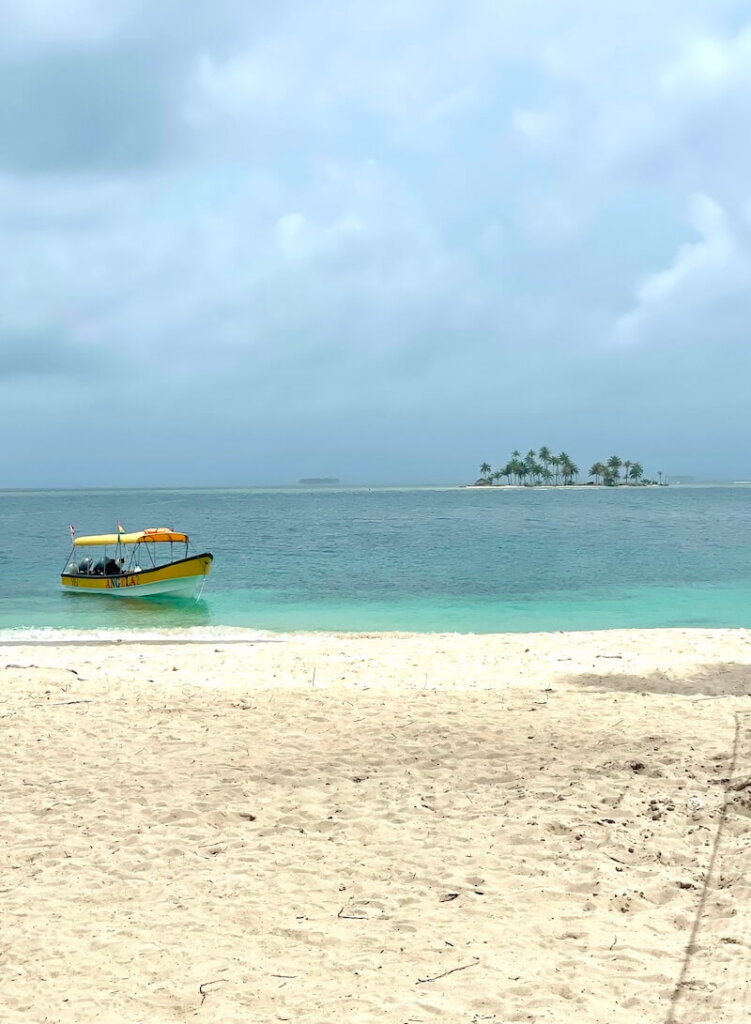 A small boat and small islands in the background and also sand