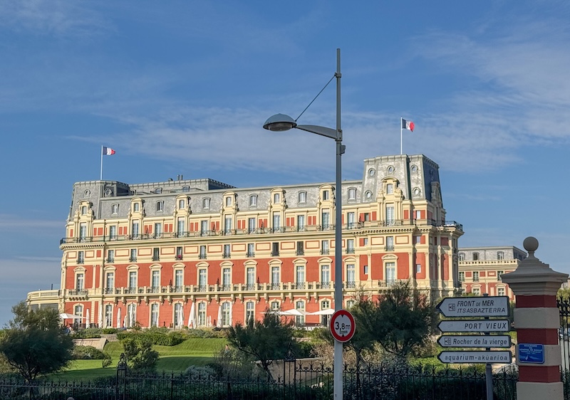 The giant luxury hotel now owned by Hyatt which was once a summer palace to Napoleon and his wife. There is a French flag atop the palace, which is painted red with a gray slate roof.