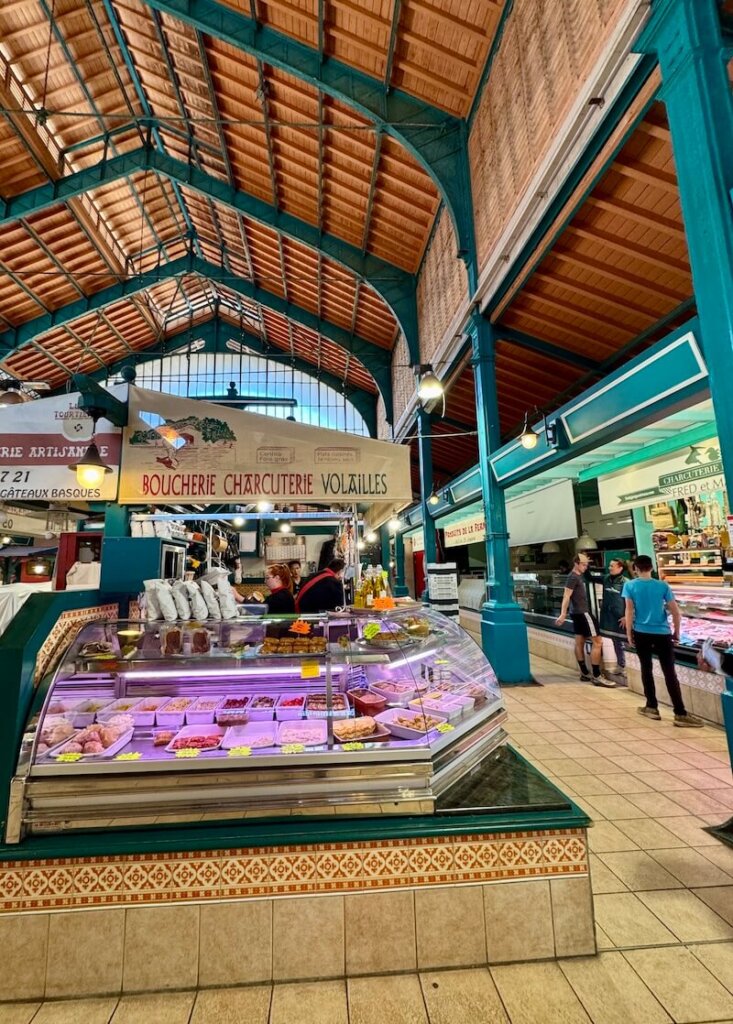 Butcher shop at Les Halles market the interior of the covered market in St Jean de Luz with a few people inside because it's about to close for the day in the afternoon