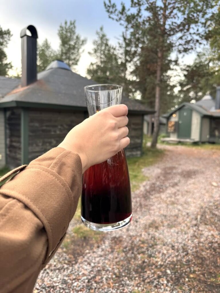 Megan, the author's friend, holding a carafe of lingonberry juice at the arrival of us to the Reindeer Lodge