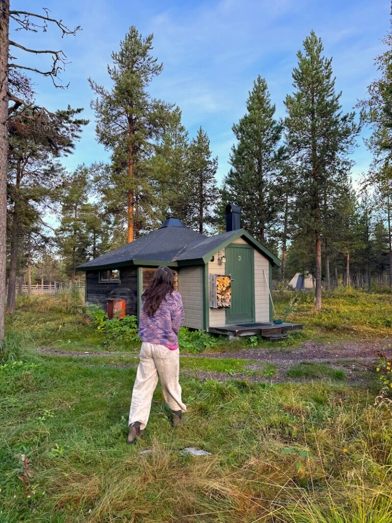 Allison Green walking around the reindeer lodge property in a purple sweater and gray jeans on an autumn morning