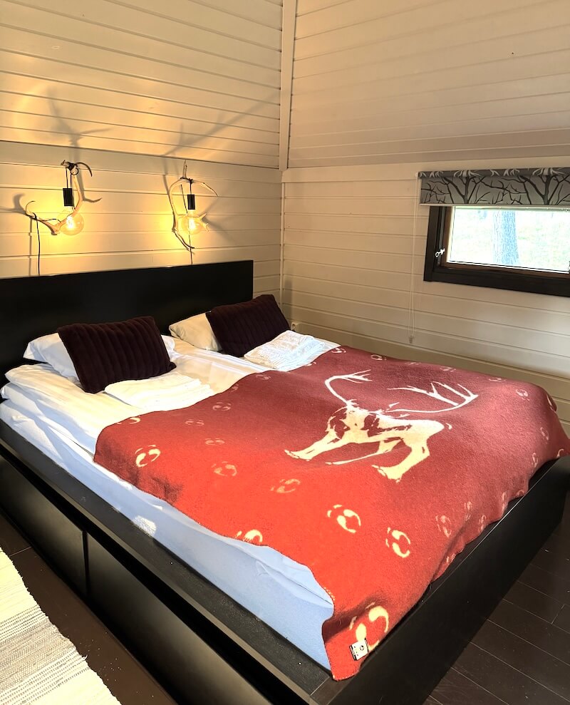 Reindeer Lodge interior with comfortable bed and antler style lamps